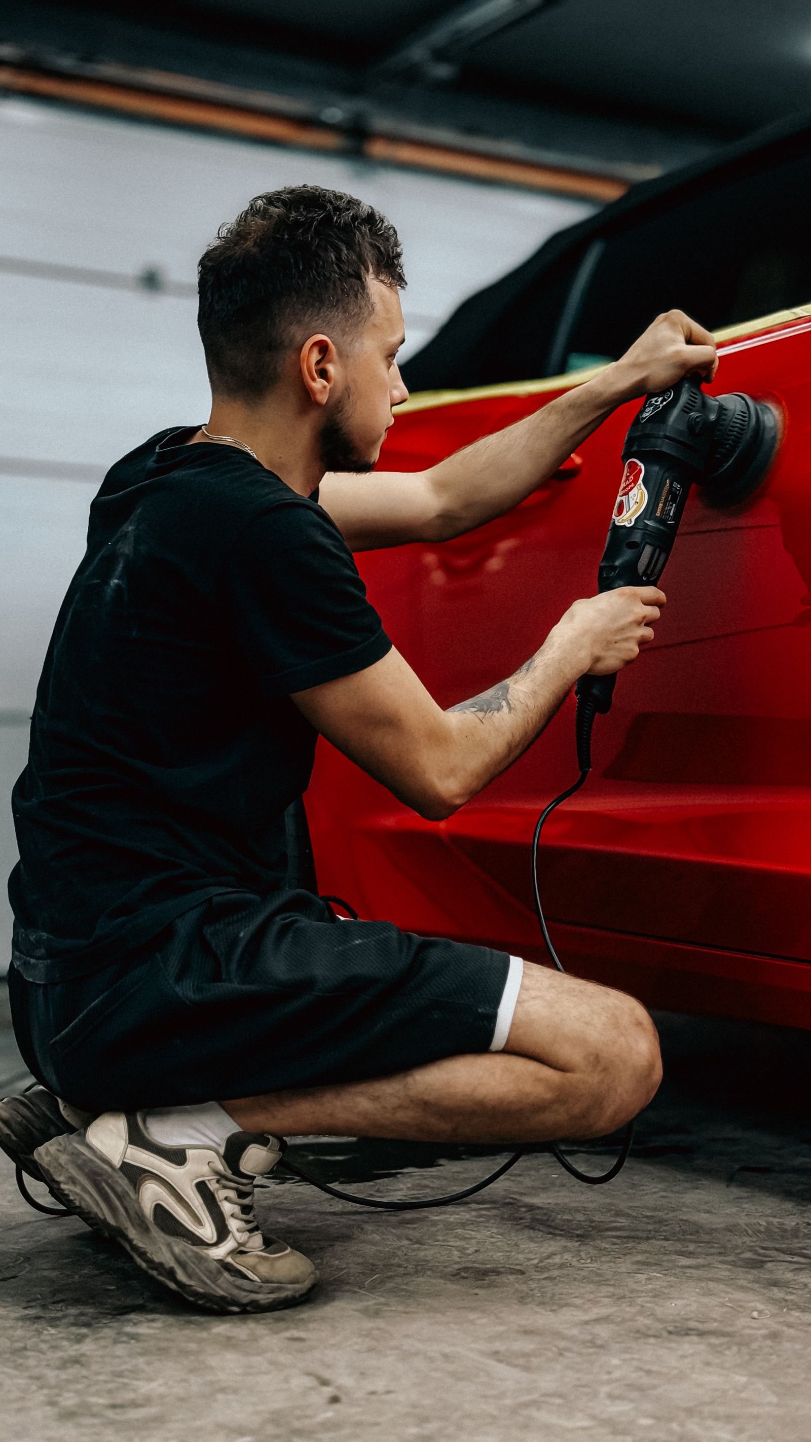 A polishing machine moving across a dark vehicle panel
