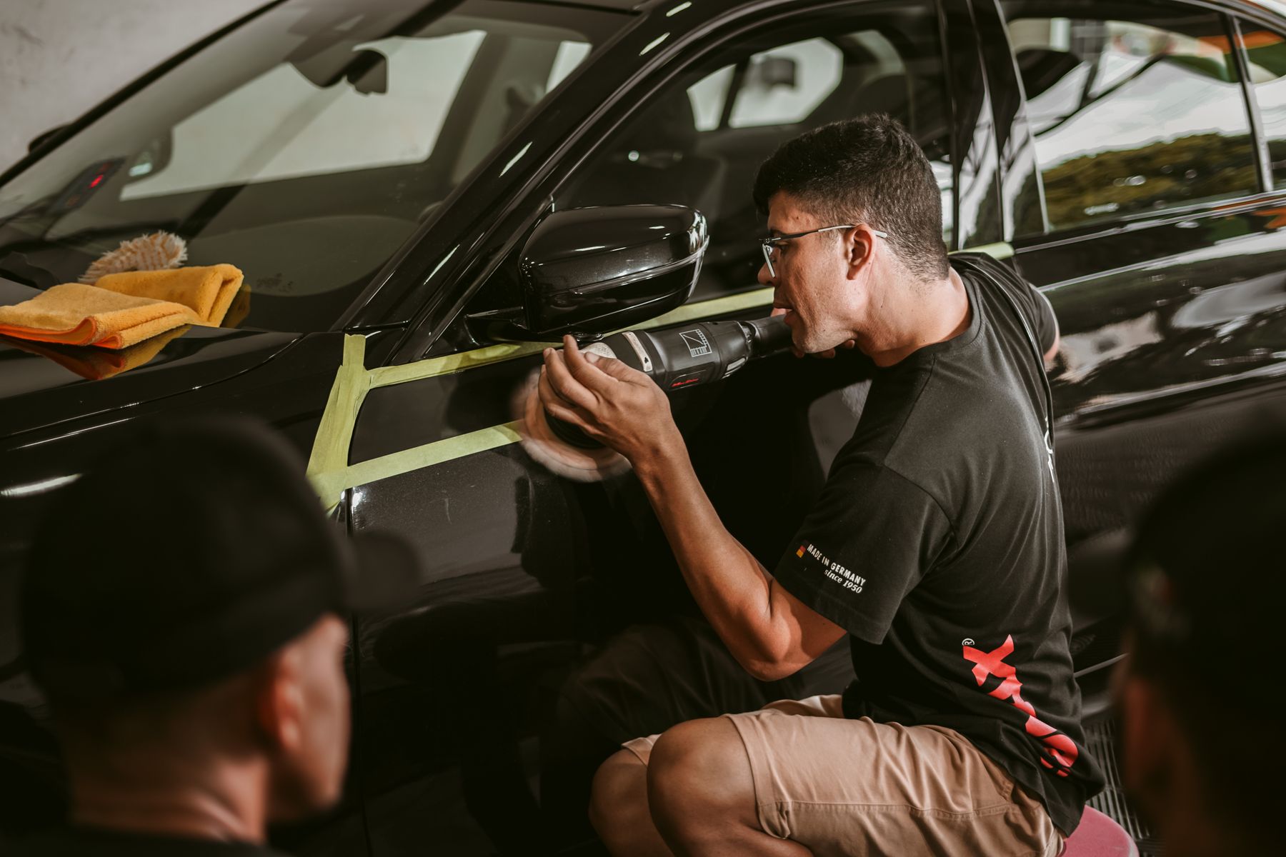 A detailer polishing the side panel of a vehicle
